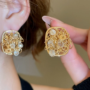 Detail of 18k gold-plated square hollow earrings with clear crystals shown on ear