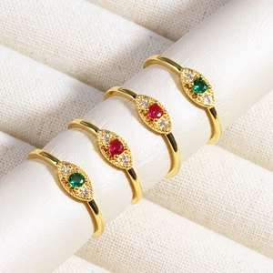 Detailed view of four gold evil eye rings with green and red emerald zircon stones
