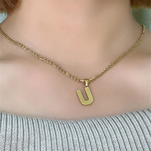 Dettaglio della collana in acciaio al titanio dorato con ciondolo lettera U martellata