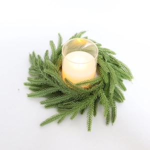 Detailed top view of lifelike Norfolk Pine candle ring with glass cup and yellow candle