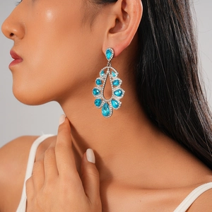 Close-up of teardrop earring with sky blue gemstones and diamonds on model side view