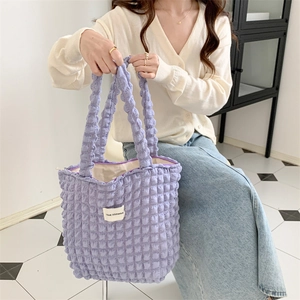 Detailed macro view of purple bubble textured fabric and white brand label on shoulder bag