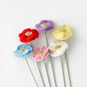 Flat lay of six handcrafted crochet poppy flowers in assorted vibrant yarn colors