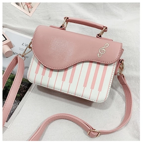Detail of piano key pattern and gold musical note embroidery on pink crossbody bag