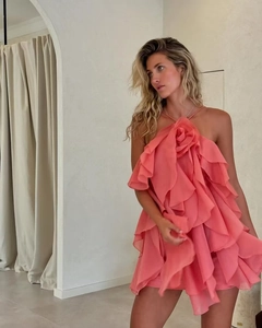 Detail of pink halter neck dress featuring 3D floral accent and layered ruffles