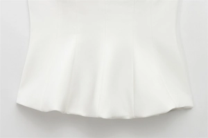 Detail of white strapless top featuring precision stitching and a wavy hem design