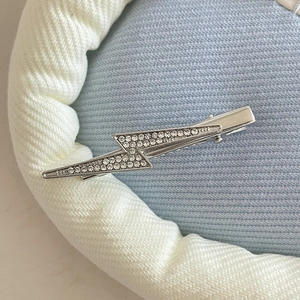 Macro view of silver lightning hair clip with sparkling rhinestones on soft fabric