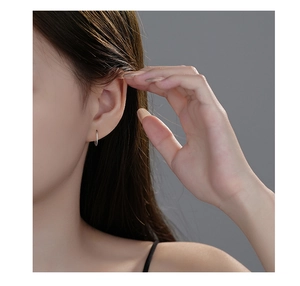 Close-up of minimalist S999 sterling silver hoop earring worn on a female ear lobe