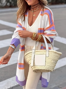 Dettaglio di cardigan a righe con borsa a secchiello intrecciata e gioielli oro