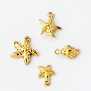 Detailed view of four golden stainless steel starfish and seashell charms for DIY jewelry