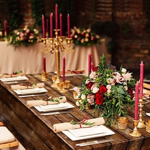 Elegant rustic wedding table setting with red roses and golden candelabras centerpieces