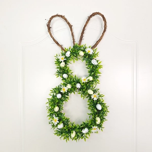 Close-up of Easter rabbit wreath with speckled eggs and white daisies on green foliage