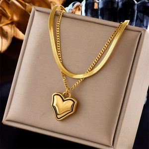 Detail of a gold double-layer necklace with a heart pendant displayed on a beige gift box