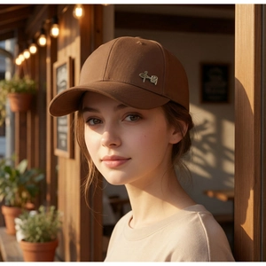 Detail of dark brown cotton baseball cap with gold metal badge on the side