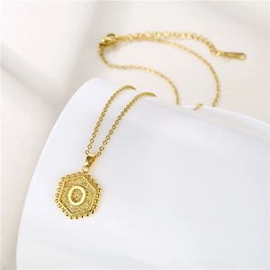 Detailed shot of golden hexagonal pendant with letter O and adjustable chain on white base