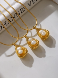Detail of three layered gold necklaces with teardrop baroque pearl pendants on snake chains