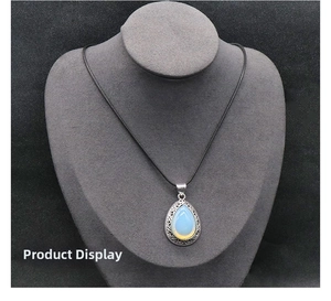 Detail of water drop moonstone pendant with intricate silver filigree on black cord