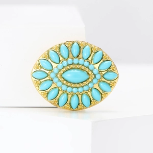 Detailed macro view of the gold-plated turquoise water drop brooch on a white pedestal