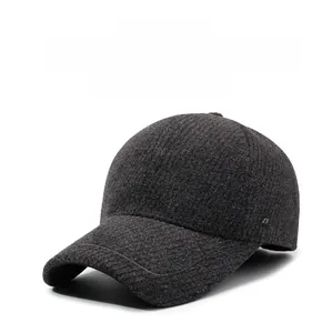Close-up of deep grey wool texture and small metal logo on winter baseball cap with earflaps
