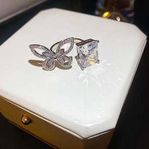 Detail of gold plated open ring with butterfly motif and emerald-cut clear stone