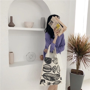 Close-up of minimalist leaf print canvas tote bag with large capacity in white room