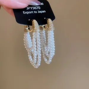 Détail de boucles d'oreilles à pampilles en perles et zircons avec finition dorée