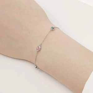 Detail of silver bracelet with colorful oval gemstones worn on wrist in soft lighting