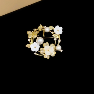 Macro detail of gold floral brooch with pearls, shell flowers and zircon crystals