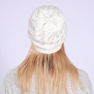 Macro view of white knitted beanie featuring intricate hollow wave pattern and soft texture