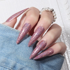 Detail of pink laser glitter on long stiletto nails with pearl ring and denim texture