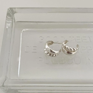 Close-up of minimalist sterling silver twisted rope stud earrings on glass tray