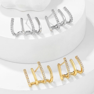 Minimalist gold and silver four-claw stud earrings with cubic zirconia inlay on white pedestals
