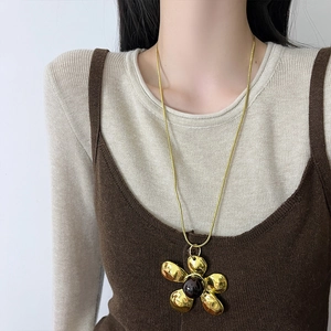Vintage gold flower pendant necklace with dark gemstone on a long snake chain