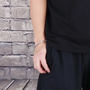 Close-up of a silver-toned titanium steel curb chain bracelet on a male model's wrist