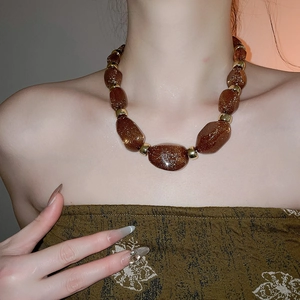 Detail of chunky irregular brown acrylic beads with gold glitter finish on a statement necklace