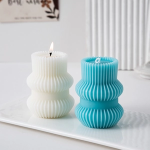 Detail of blue ribbed geometric pillar candle on a white tray with minimalist decor