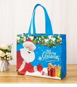 Close-up of blue Christmas non-woven gift bag with Santa Claus and Merry Christmas print