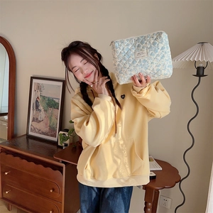Quilted floral makeup bag shown with yellow hoodie in a cozy aesthetic lifestyle setting