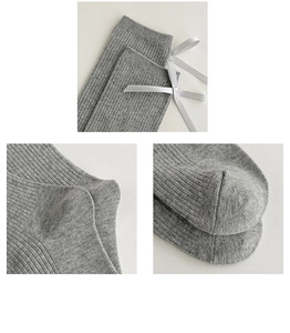 Close-up of gray knit socks featuring white bow ribbons and vertical ribbed texture