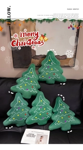 Close-up of soft plush Christmas tree pillows with colorful embroidery on a sofa