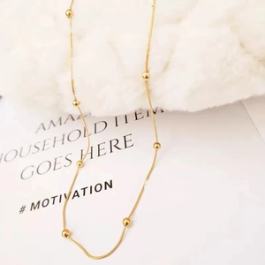 Detail of 18K gold-plated snake chain necklace with beads on soft white faux fur