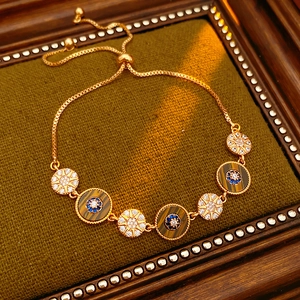 Detail of vintage gold bracelet with zircon stars and tiger eye charms on green fabric