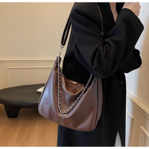 Detail of dark brown hobo shoulder bag with silver chain strap and vertical stitching