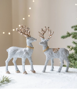 Detail of silver glitter reindeer figurines with gold sequins on a snowy winter background