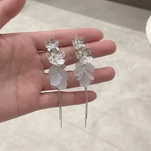 Détail des boucles d'oreilles feuilles avec perles et pompons argentés