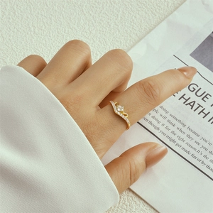 Close-up of a double-layered gold ring with teardrop diamonds worn on a finger