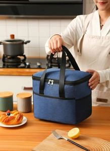 Detail of blue insulated lunch bag featuring double handles and durable zippers in a kitchen
