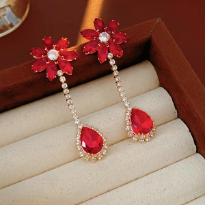 Macro view of red flower drop earrings with rhinestones in a velvet jewelry box