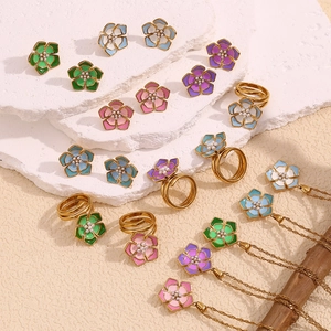 Detail of floral jewelry set with enamel petals and pearls on a textured stone base