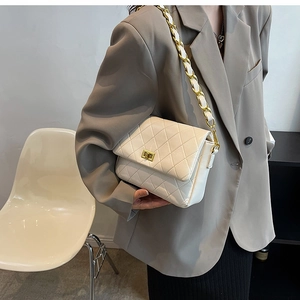 Detail showing the quilted faux leather texture and golden chain strap of the white crossbody bag